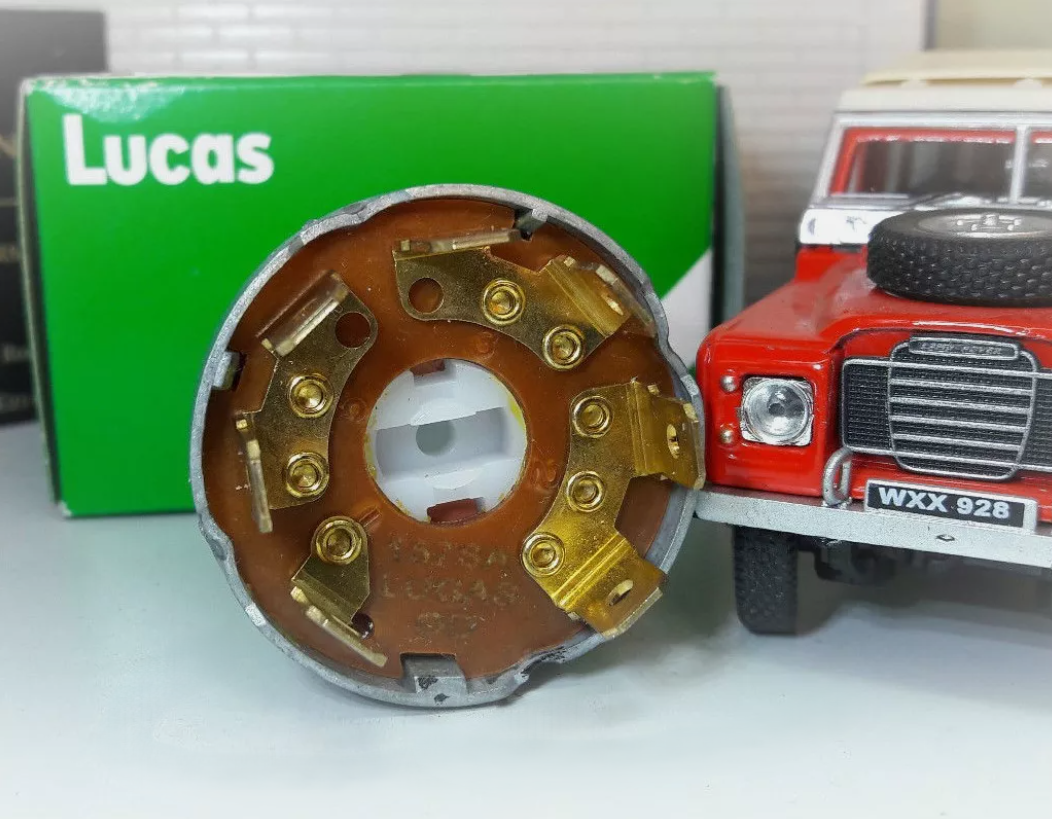 Rear view of a Series 3 Petrol Ignition switch showing 7 brass spade terminals, stood in front of a green Lucas Box.