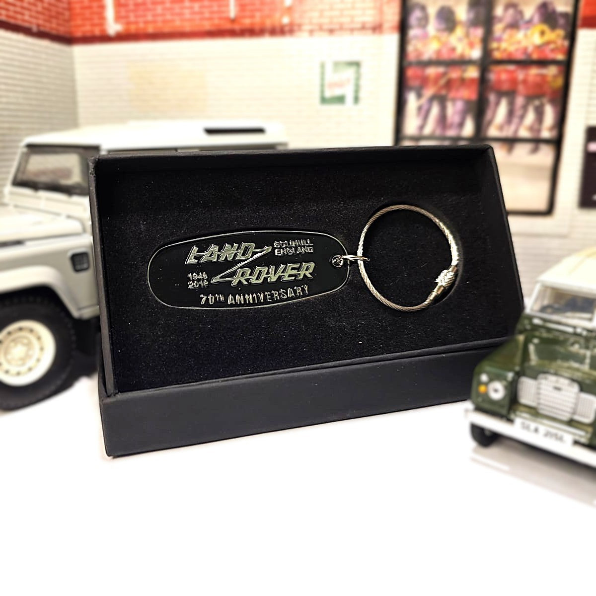 Land Rover keychain in a black box with 'Land Rover' branding, set against a blurred indoor background.