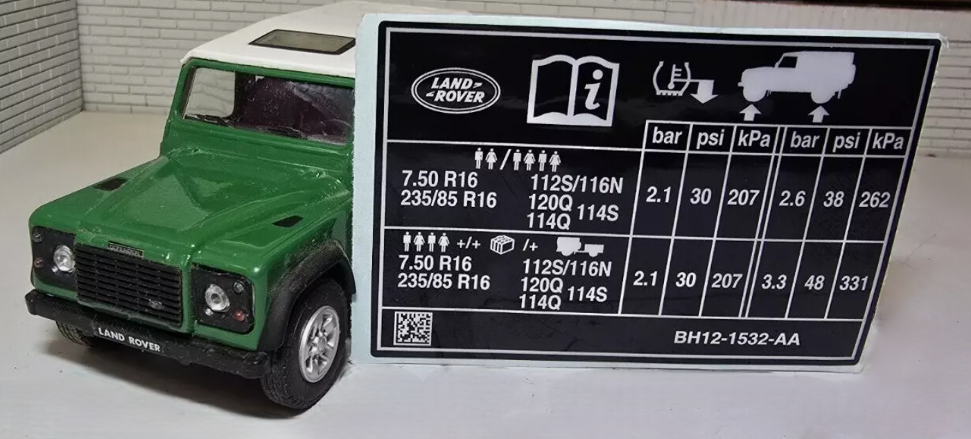 Land Rover Defender 90 Tyre Pressure Decal, leant up against a Green Model Defender.