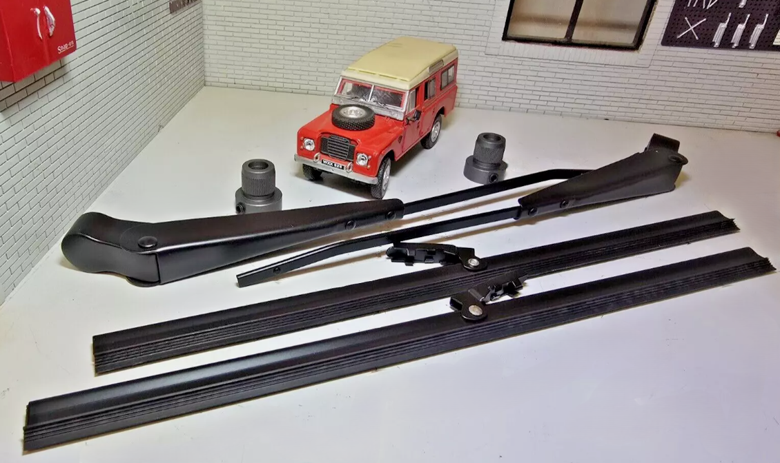Wiper Blades and Wiper Arms in Stainless Steel and Spindle Adapters Kit in Black. Behind is a Red model Land Rover for Illustration Purposes.