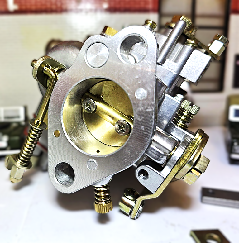 Close-up of a mechanical carburetor with brass and metal components on a blurred background.