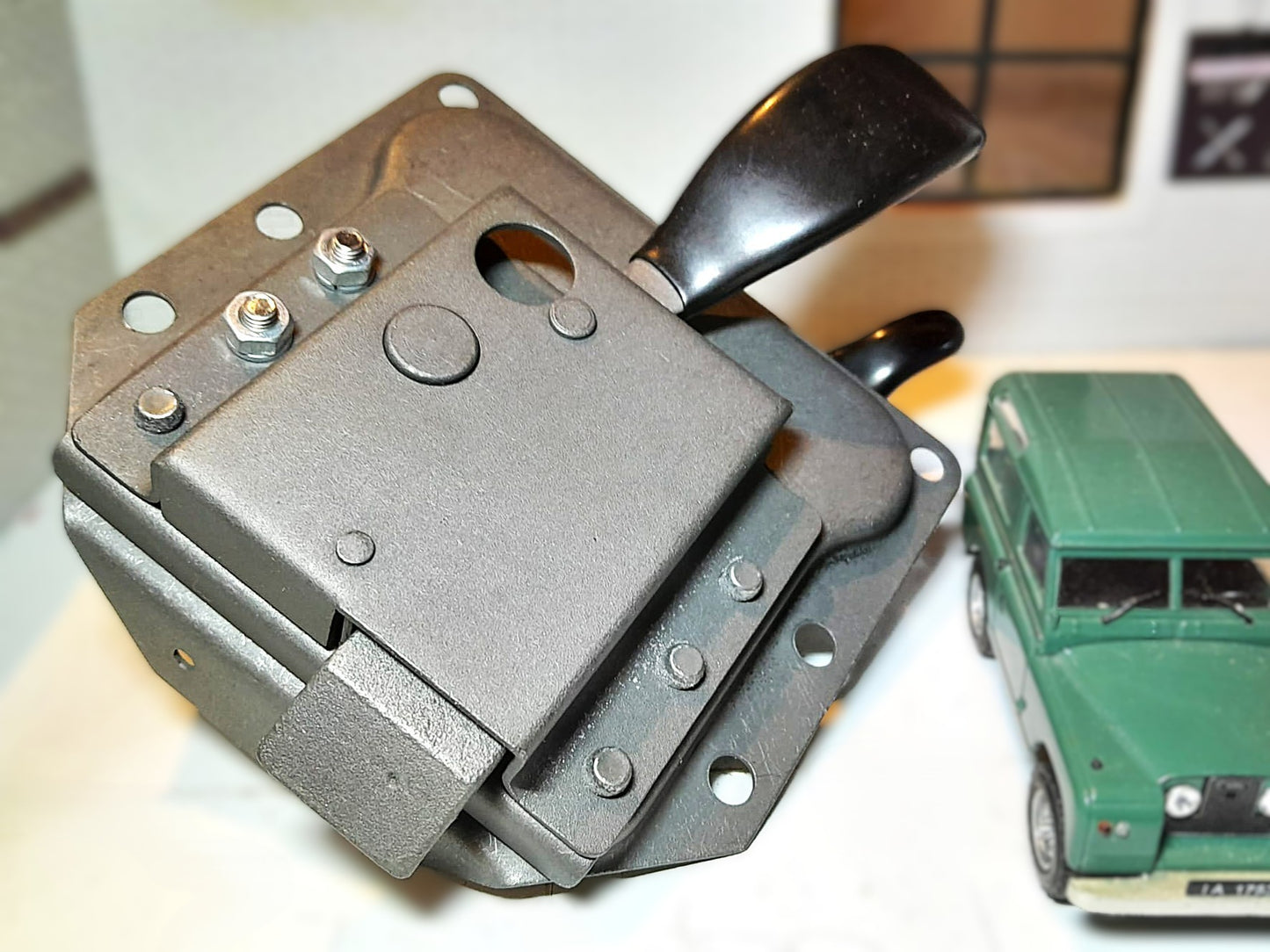 Metallic mechanical device with a green toy car in the background