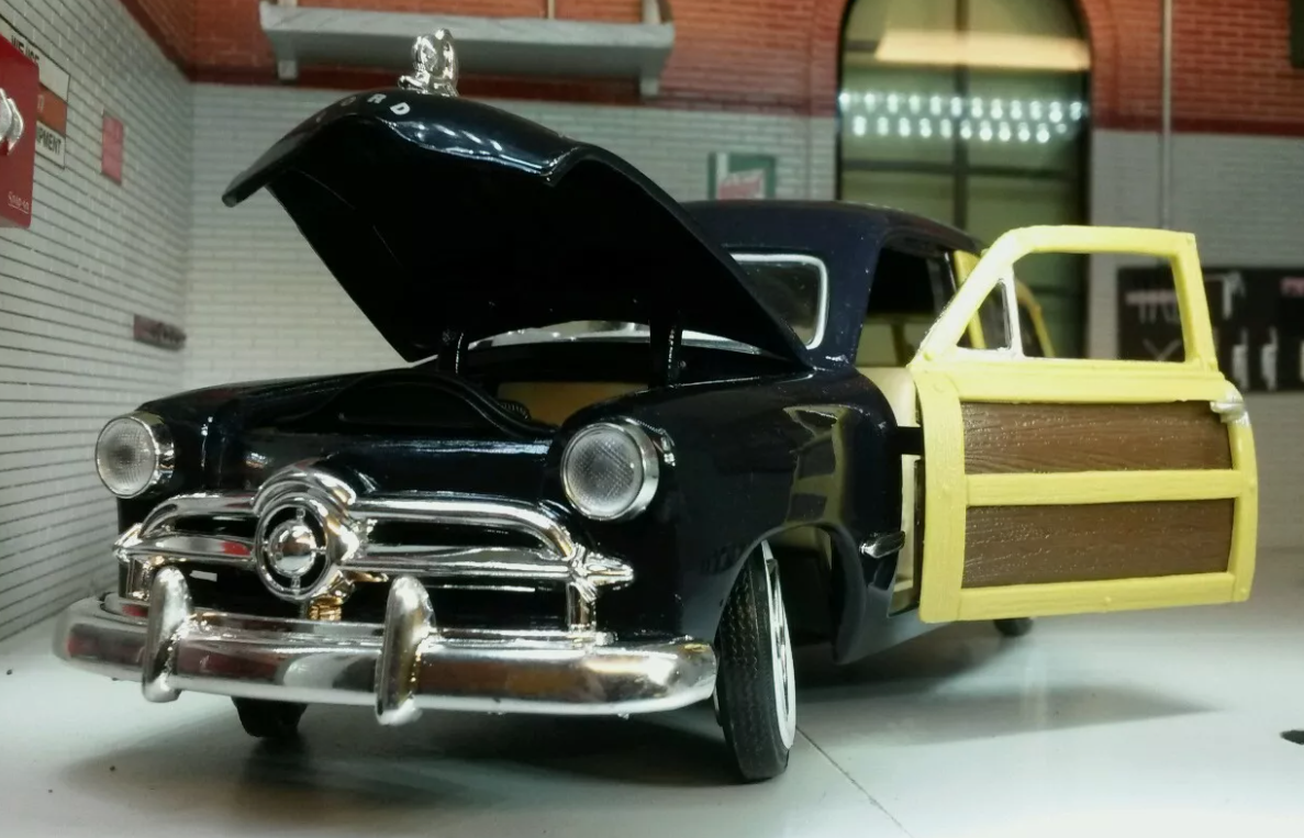 Front view of a 1949 Ford Woody Station Wagon in black. The bonnet and the "wood panel" door is open.