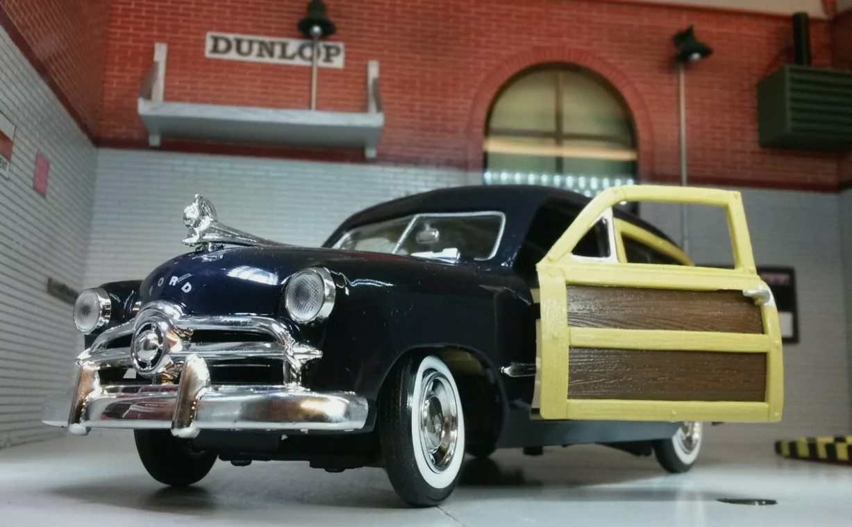 Front quarter view of a 1949 Ford Woody Station Wagon in black. The "wood panel" door is open.
