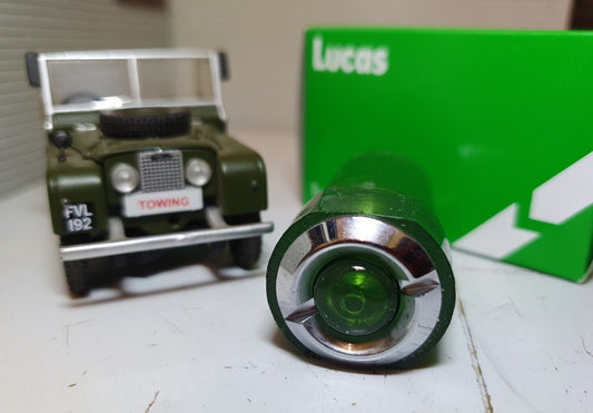 Front View of a Green Warning Light With Chrome Bezel with A Model Land Rover and Lucas Box in the Background