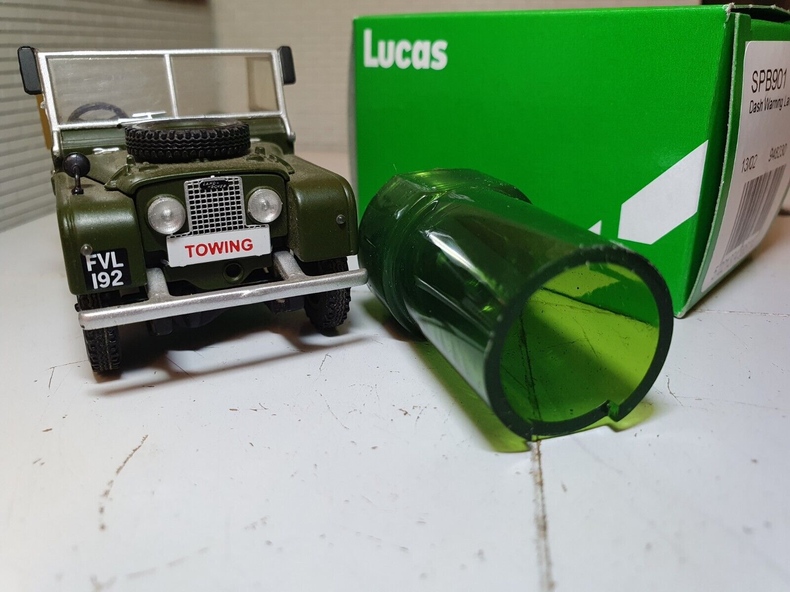 Rear View of a Green Warning Light With Chrome Bezel with A Model Land Rover and Lucas Box in the Background